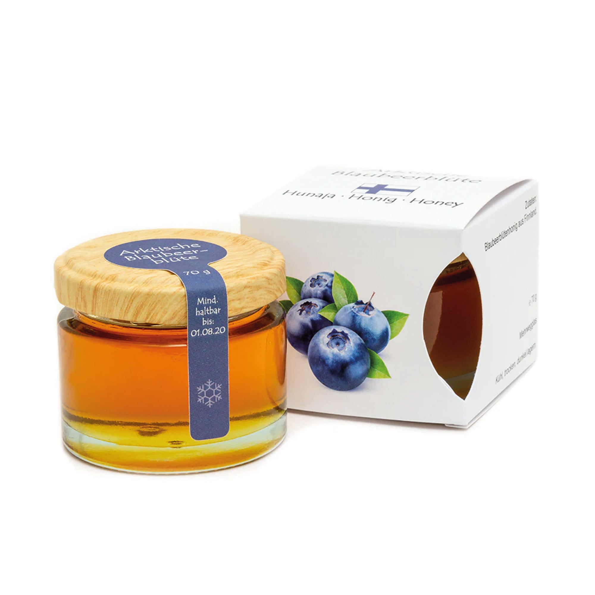 Ein Glas Arktischer Blaubeerblütenhonig mit Holzdeckel und blauem Etikett neben einer Verpackung mit Blaubeermotiven.